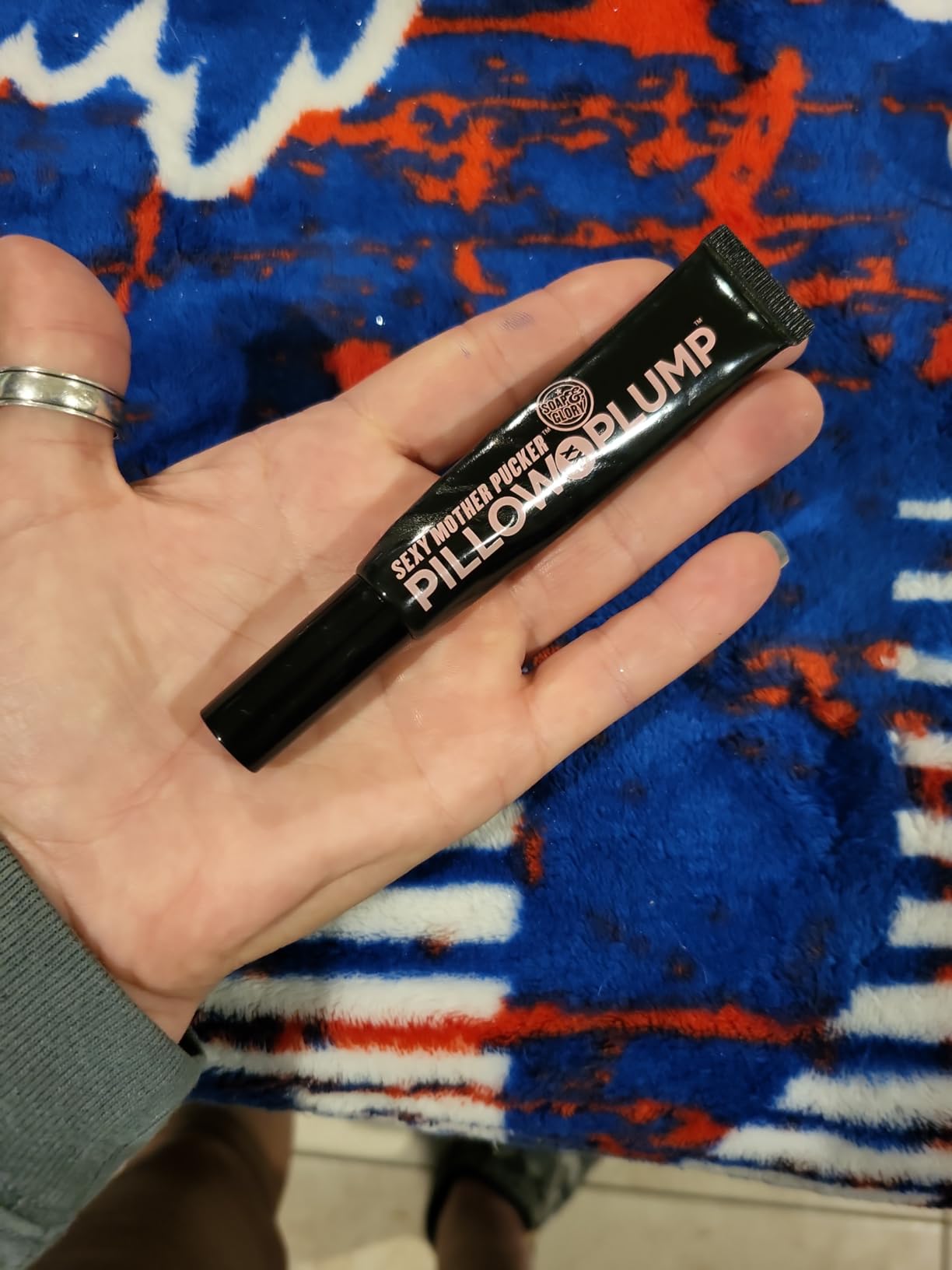 A black Soap & Glory Sexy Mother Pucker Pillow Plump XXL lip gloss tube held flat in a palm